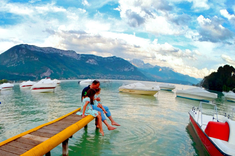 Familia numa praia com barcos, em Annecy, França