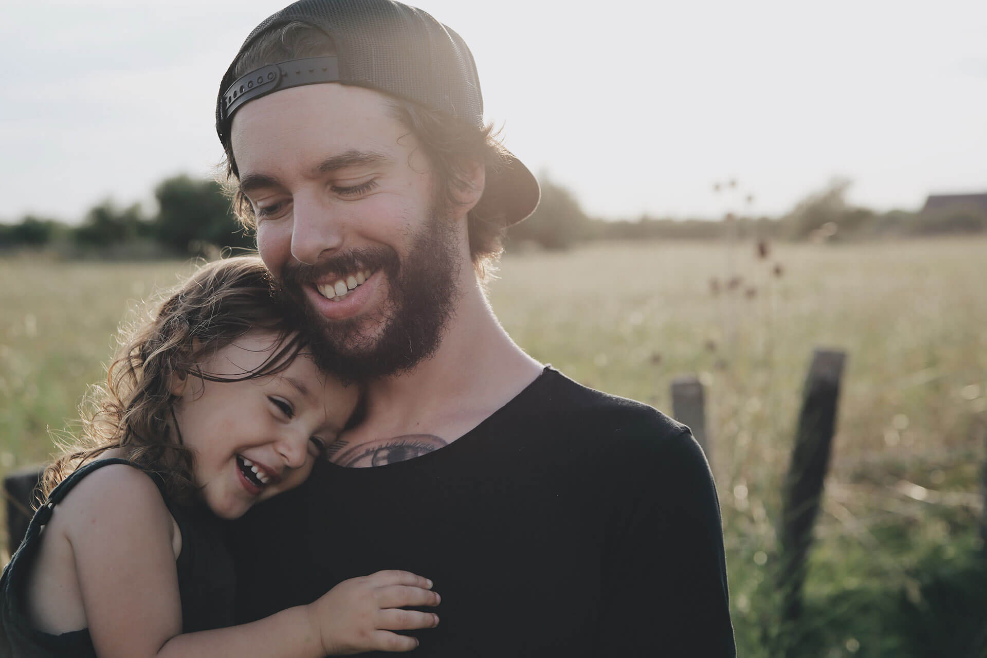 Pai com menina ao colo no campo.