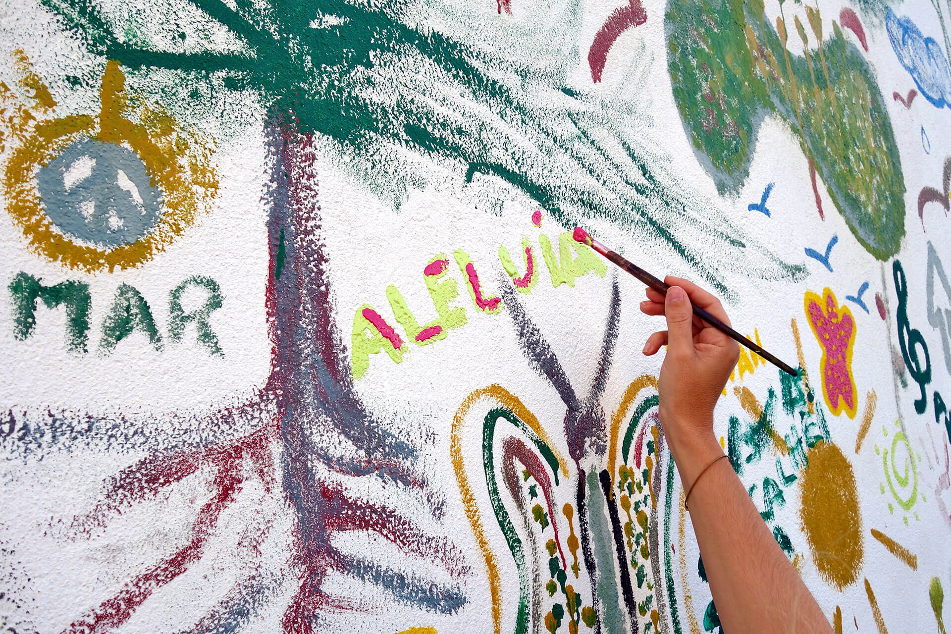 Mão segura num pincel para pintar parede com motivos relacionados com PNL