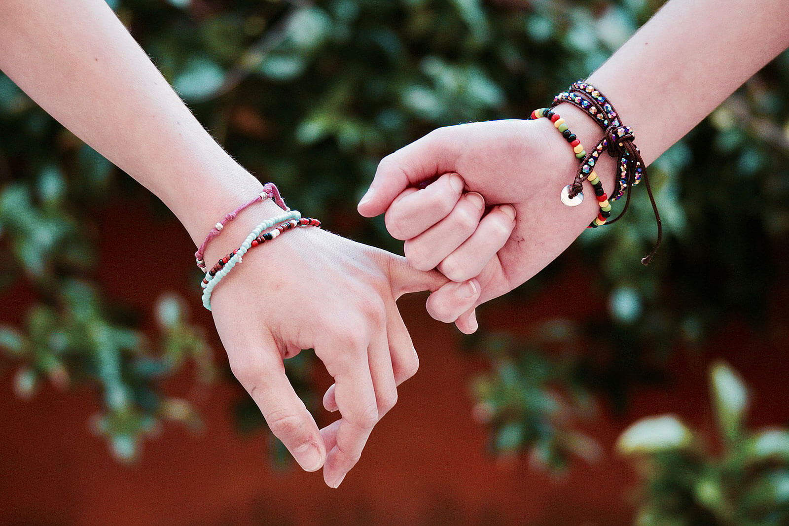 Pulseiras em braços com mãos dadas.