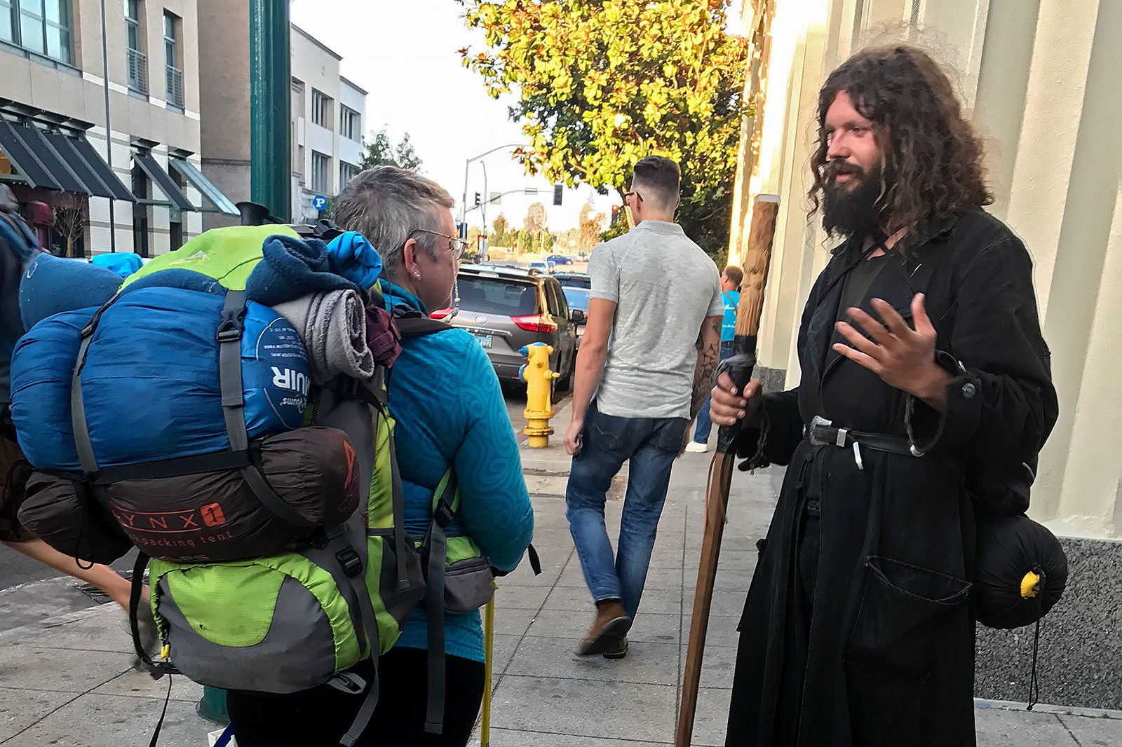 Homem com aspecto de Jesus, falando com mochileiro na rua