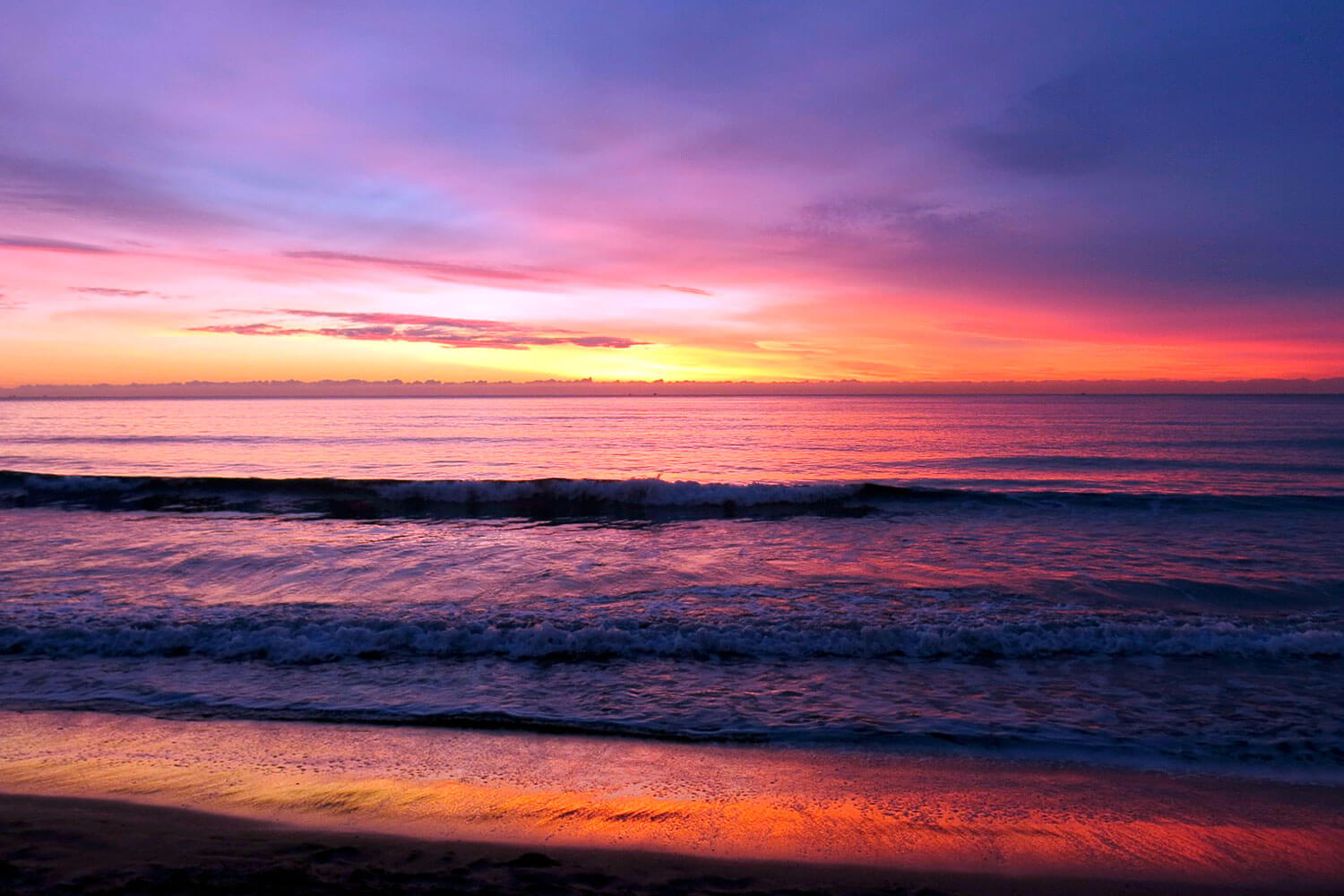 Orange shades of sunset on a beach with calm ripple