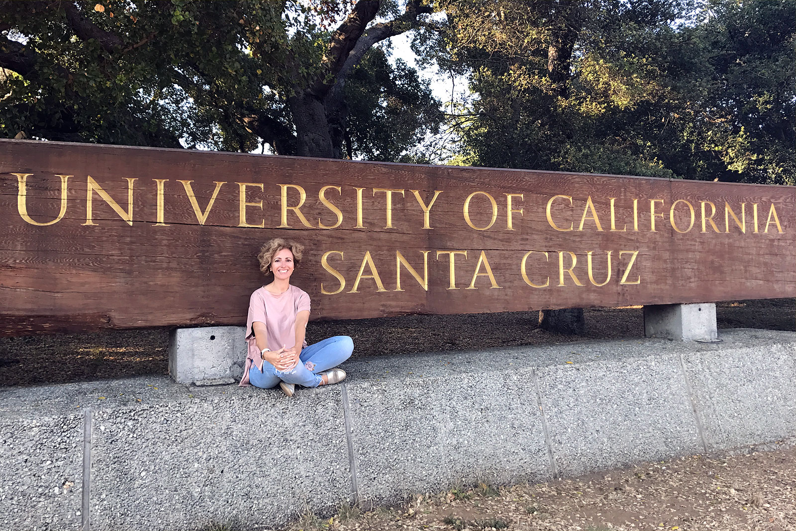 Rita Aleluia sentada junto identificador Universidade Santa Cruz, na California