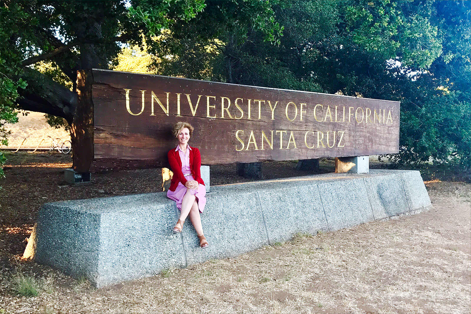 Rita Aleluia sentada junto identificador Universidade Santa Cruz, na California