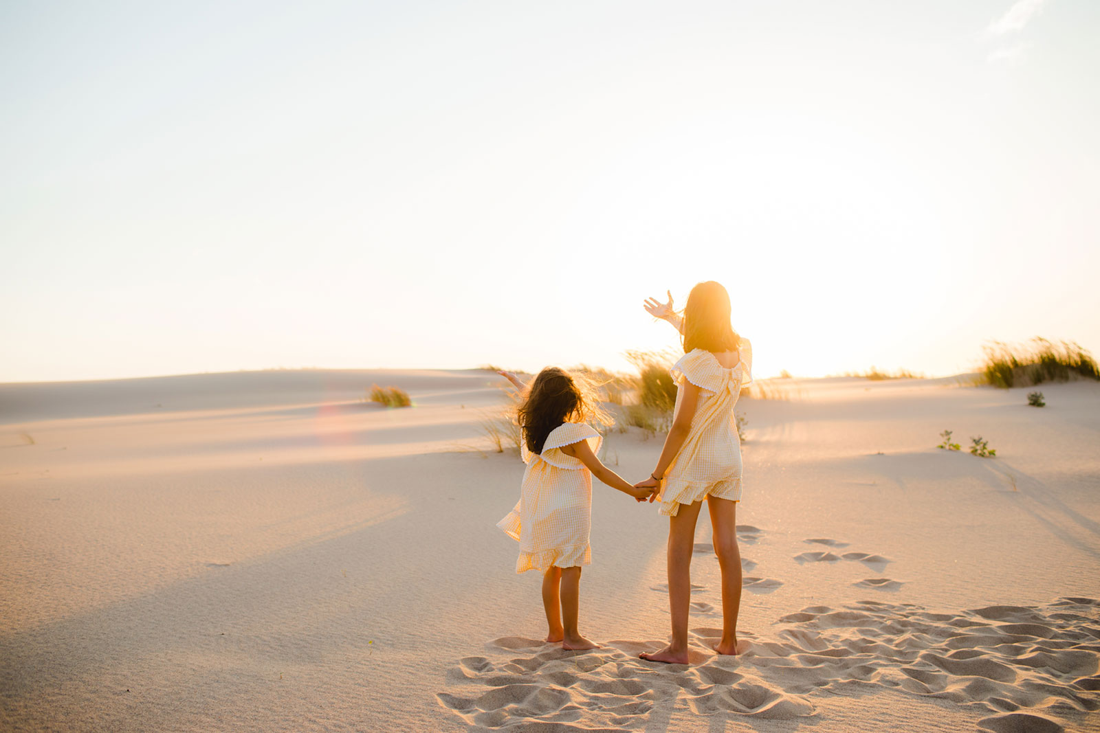 Crianças de mãos dadas numa praia ao pôr-do-sol