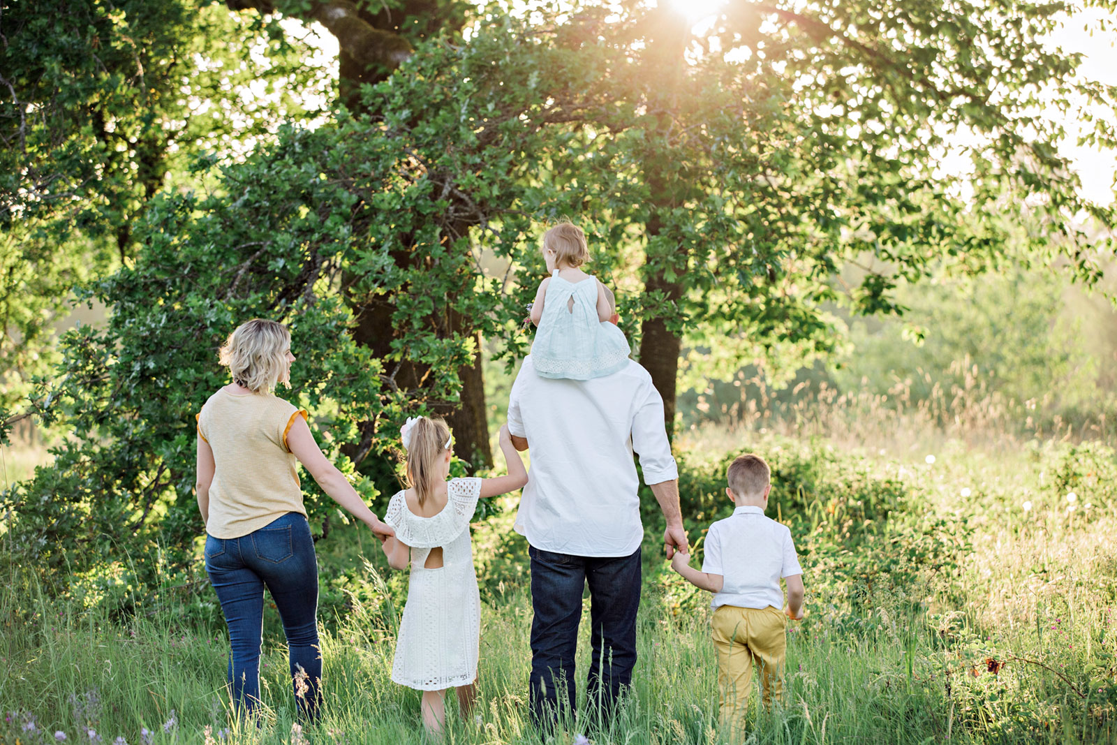 Família a passear num bosque, durante um dia com muito sol