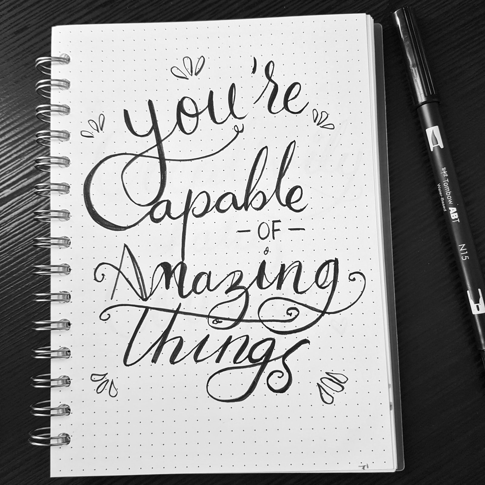 Caderno com frase "You'are Capable of Amazing Things", sobre mesa junto a caneta