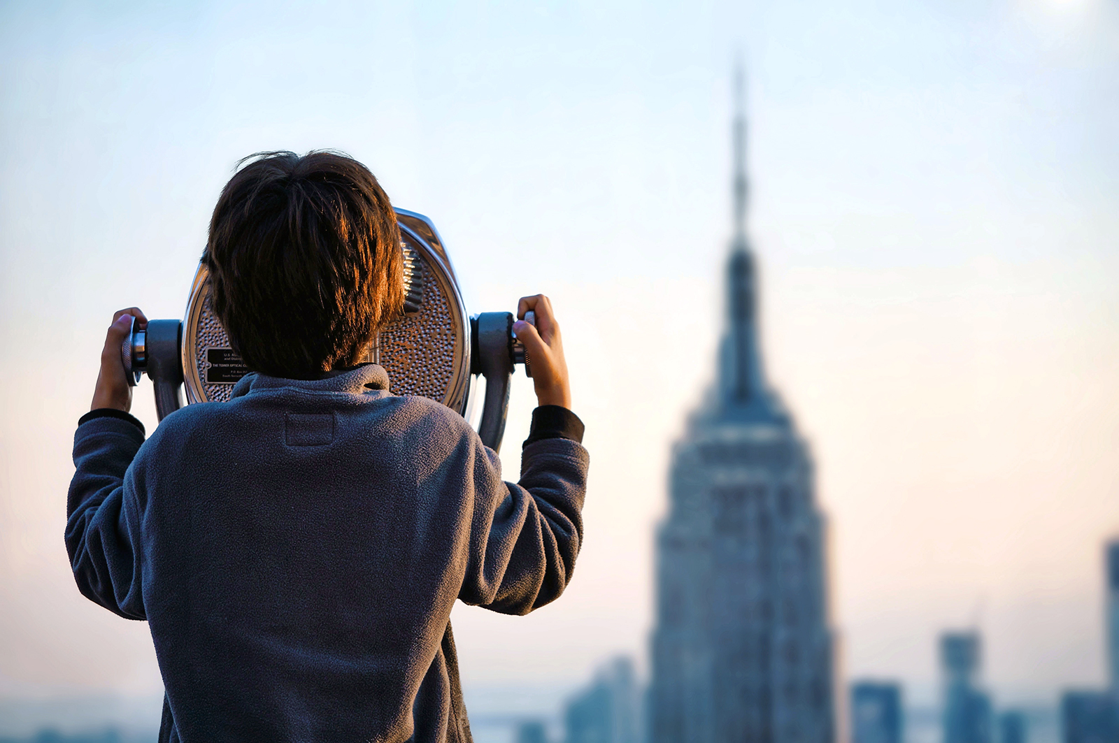 Criança a ver com binóculos o Empire State Building, em Nova Iorque.